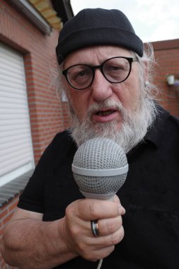 Elinde kocaman bir mikrofon olan bir muhabir sorular soruyor.