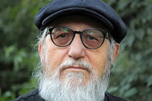 stock image Portrait of a senior man with a stylish flat cap looking seriously into the camera