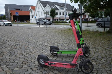 Stavanger, Norveç - 5 Ağustos 2024 Pembe ve yeşil elektrikli scooter bir sonraki kullanıcıyı bekliyor
