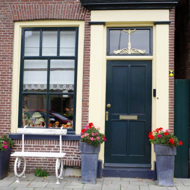 Anıt koruması altında olan bir evin ön kapısı ve penceresi. Nijkerk, Hollanda 'nın kültürel mülkiyetinin amblemi kapının solunda.