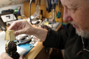 Yaşlı bir adam eşit derecede eski bir mikrofonu tamir ediyor. Değiştirmek yerine tamir et