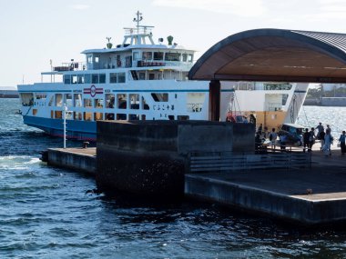 Hiroshima, Japan - August 24, 2018: Passengers and vehicles boarding Ninoshima ferry boat at Ujina passenger terminal of Hiroshima port clipart