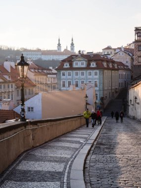 Prag, Çek Cumhuriyeti - 13 Aralık 2018: Soğuk bir kış akşamında Mala Strana mahallesindeki pitoresk caddede yürüyen insanlar