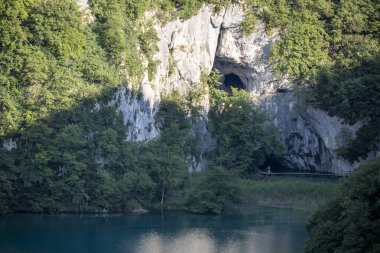 Plitvice gölleri ulusal parkının dağ mağaraları, gün batımında, sarp kayaları kaplayan yoğun, yeşil ağaçlarla