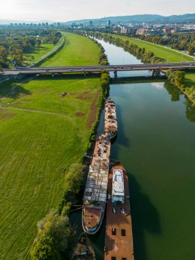 Zagreb, Hırvatistan-17 Eylül 2023: Gençlik Köprüsü ve Sava nehri kıyısında demirlemiş ünlü ve terk edilmiş nehir gemilerinin havadan görünüşü