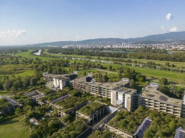 Zagreb, Hırvatistan-26 Eylül 2023: Hırvatistan 'ın Zagreb kentindeki Sava nehir setinde doğa ve büyüyen bitki örtüsü tarafından ele geçirilen terk edilmiş ve fazla büyümüş hastane merkezinin havadan görünüşü