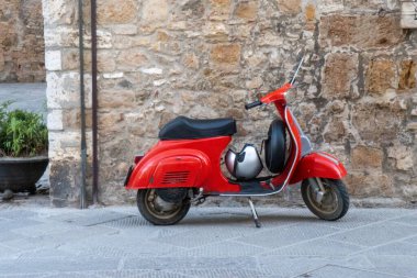 İtalya 'da büyüleyici bir ortaçağ köyünün arka planında kırmızı bir Vespa göze çarpıyor. Yüksek kalite fotoğraf