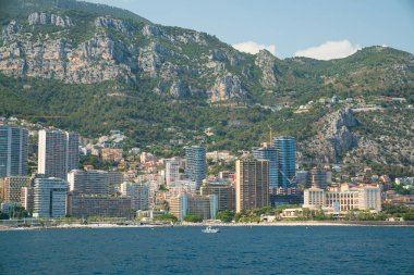Monte Carlo kıyı şeridi. Arka planda dağlar ve kıyıya yakın binalar var.