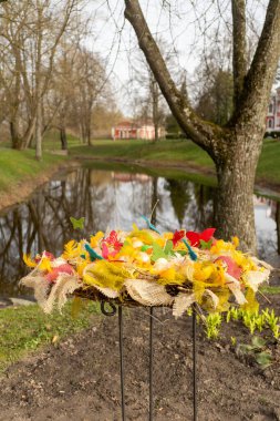 Dallarından sarkan paskalya yumurtalarıyla süslenmiş sarı çiçekli yaprak döken bir ağaç tuhaf bir doğal manzara yaratıyor.
