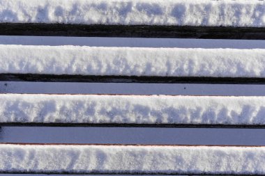 Açık havada izleyiciler için arka arkaya kar kaplı banklar, soğuk hava, sığ bir alan derinliği ile fotoğraflanmış, alçak bir bakış açısından, akşam ışığı