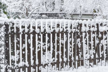 Kar fırtınasına sarılmış eski bir ahşap çit, tozlu bir bahçe, ön planda çekilen çitler, tozlu bir bahçe görünür, özel bir evin bahçesi, hava koşulları fırtınalı bir kar fırtınası.