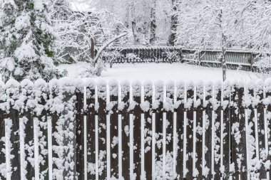 Kar fırtınasına sarılmış eski bir ahşap çit, tozlu bir bahçe, ön planda çekilen çitler, tozlu bir bahçe görünür, özel bir evin bahçesi, hava koşulları fırtınalı bir kar fırtınası.