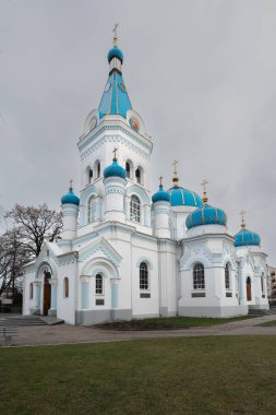 Letonya 'nın Jelgava kentindeki bir caddenin kenarındaki kar yağışı sırasında St. Simeon ve St. Anne Ortodoks Kilisesi. Fotoğrafta kilisenin kubbeleri, önünde bir çit ve ağaçlar var..