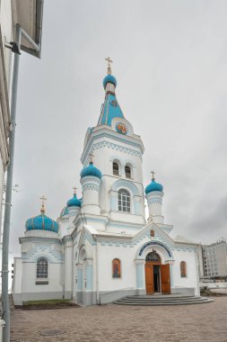 Letonya 'nın Jelgava kentindeki bir caddenin kenarındaki kar yağışı sırasında St. Simeon ve St. Anne Ortodoks Kilisesi. Fotoğrafta kilisenin kubbeleri, önünde bir çit ve ağaçlar var..