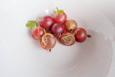 Beyaz bir kasede birkaç olgun bektaşi üzümü var. Bir dut ikiye bölünür ve eti ve tohumları ortaya çıkar. Arka plan temiz, beyaz bir kase.