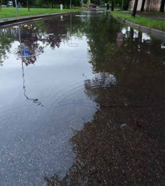 Sel, kaldırım ve çöp konteynırının altında büyük bir su birikintisi. Çevreyi, ağaçları, gökyüzünü yansıtıyor. İlginç bir soyut etki yaratıyor.