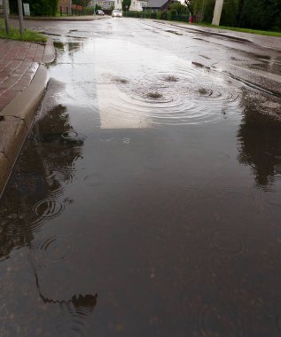 Sel, kaldırım ve çöp konteynırının altında büyük bir su birikintisi. Çevreyi, ağaçları, gökyüzünü yansıtıyor. İlginç bir soyut etki yaratıyor.