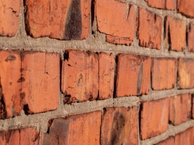 Kırmızı tuğlalı bir duvarın detaylı yakın plan görüntüsü, dokusunu, yıpranmasını ve benzersiz desenini gösteriyor. Geçmişler, mimari çalışmalar veya klasik ve kentsel temalar için ideal.