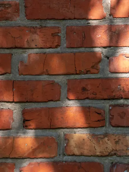 Klasik bir kırmızı tuğla duvarın detaylı çekimi tuğlaların ve çimento harcının düzensiz dokusunu gösteriyor..