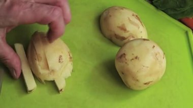 Adım adım patatesler yeşil bir kesme tahtasında doğranıyor.