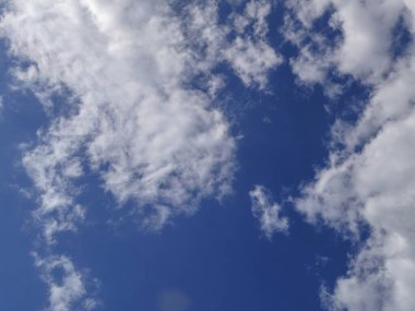 Yumuşak, kabarık bulutların uçsuz bucaksız mavi gökyüzüne karşı huzurlu bir manzarası..