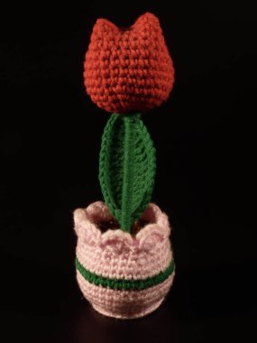 Bright handmade yarn flower decoration against a dramatic black background