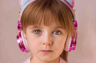 Kablosuz kulaklıklarla güzel bir kızın portresi. Yüzü yakın. Çocuksu duygular, seçici odaklanma.
