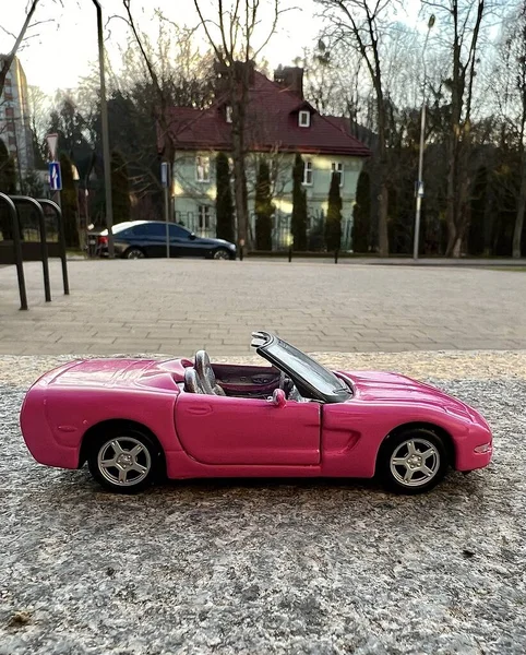 Pink car toy cabriolet on the city street, car for girls, speed and comfort in a luxury car, selective focus