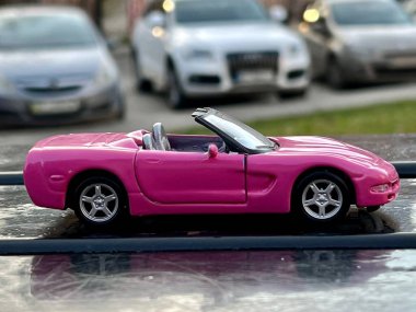 Lviv Ukrayna - 04 01 2023: Pembe araba oyuncak Cabriolet şehir sokaklarında, kızlar için araba, lüks bir arabada hız ve konfor, seçici odaklı