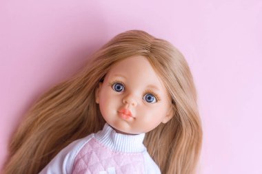 Plastic doll with blue eyes and blond hair portrait close-up, modern toys Spanish vinyl doll, selective focus