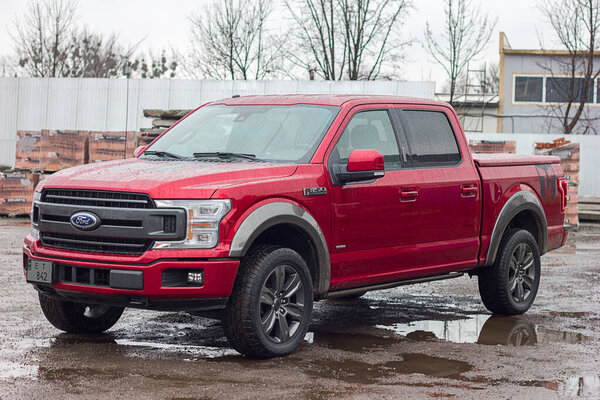 Lviv Ukraine - 12242022: Ford F-150 display red at the dealership. Ford F150 is available  XL, XLT, Lariat, King Ranch, Platinum and Limited models.SUV Ford F150 Platinum in the parking lot  in rainy