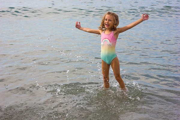 美しい幸せな女の子が波で遊んで海に飛び出す ロイヤリティフリーのストック画像