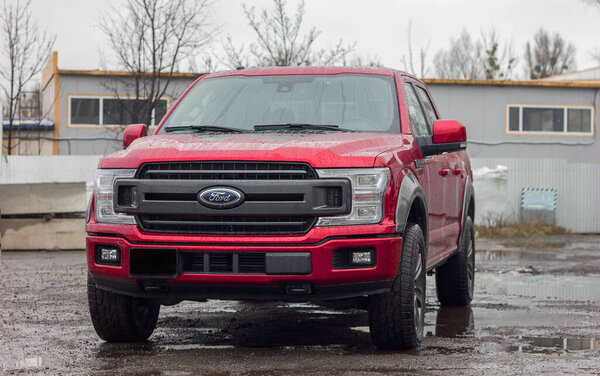 Lviv Ukraine - 12 24 2022: Ford F-150 display red at the dealership. Ford F150 is available  XL, XLT, Lariat, King Ranch, Platinum and Limited models.SUV Ford F150 Platinum in the parking lot  in rainy