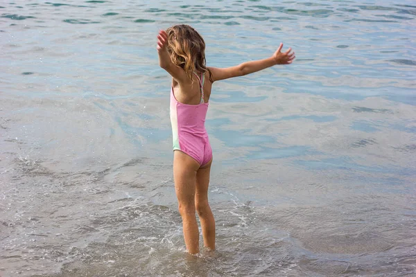 美しい幸せな女の子が波で遊んで海に飛び出す ストックフォト