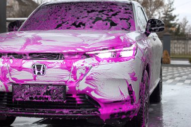 Lviv Ukrayna - 11 05 2023: Pembe köpükle oto yıkamada Honda elektrikli araba
