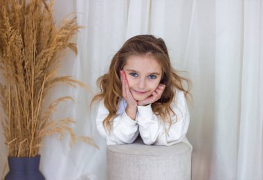 Minimalist iç mekanda, seçici odak noktasında fotoğraf çekimine gülümseyen güzel küçük kız.