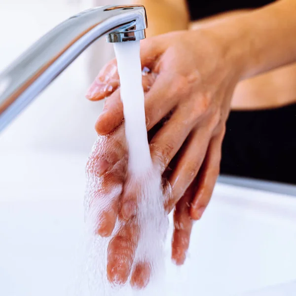 Women\'s hands under tap water close-up, soft selective focus. Wash hands under running water, hygiene
