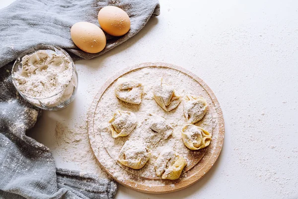 丸みを帯びた板にイタリアのトルテリーニや餃子は小麦粉を振りかけた 調理プロセスです イタリアの伝統的なトルテリーニパスタ料理スタイル — ストック写真