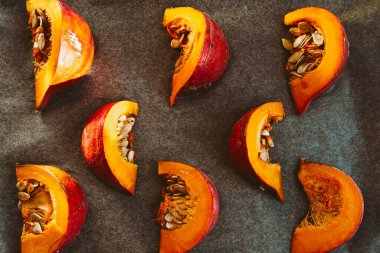 Pişirme parşömeninde kemikleri olan balkabağı dilimleri. Çiğ balkabağı kabağı kabağı kabağı, yumuşak odak, sebze yemeği.