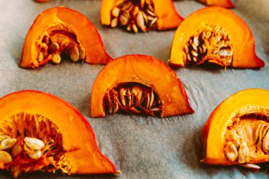 Pişirme parşömeninde kemikleri olan balkabağı dilimleri. Çiğ balkabağı kabağı kabağı kabağı, yumuşak odak, sebze yemeği.