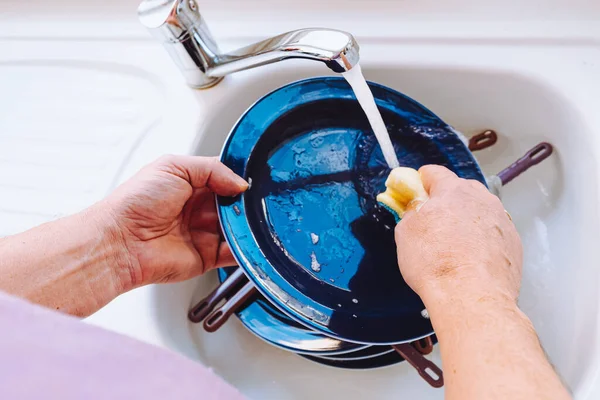 men\'s hands washing dishes in sink with detergent. man doing homework washes large pile of dishes in kitchen sink, household chores, routine, duties