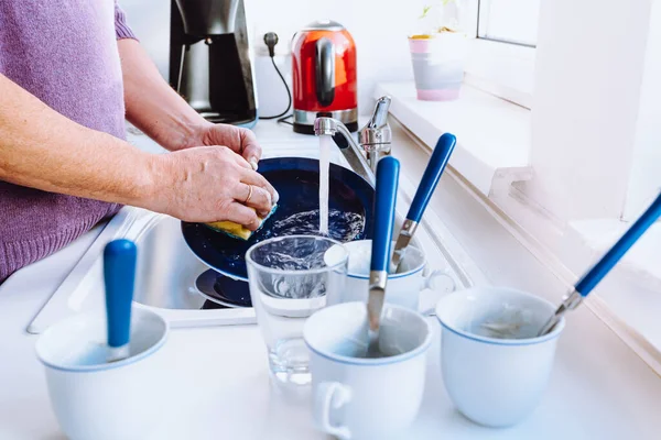 men's hands washing dishes in sink with detergent. man doing homework washes large pile of dishes in kitchen sink, household chores, routine, duties