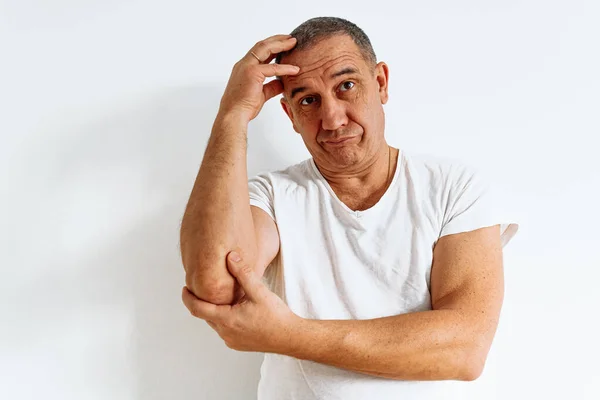 portrait of attractive middle-aged man with brown eyes, muscular build, wearing white t-shirt, with skeptical expression, dissatisfied emotion, doubtful opinion