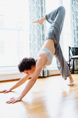 Athletic young woman doing stretching exercises in the living room. Yoga home workout, stretching in the morning. teenager girl with brown hair, in cosmetic cream mask, does muscle stretching, trains at home, yoga