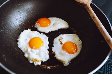 three eggs fried in frying pan scrambled eggs. Healthy food, nutritious delicious breakfast