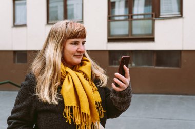 Mature woman using a mobile phone in the city. Outdoor lifestyle portrait.
