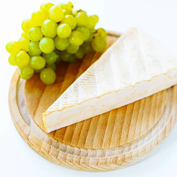 Queso Brie Sobre Tabla Redonda Madera Con Racimo Uvas Blancas — Foto de Stock