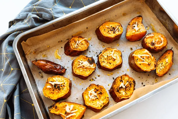 Baked sweet potato slices with herbs and olive oil on craft paper for baking in baking sheet