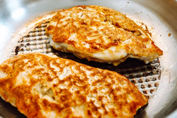 stock image Breaded chicken meat on a grill pan. Fried chicken fillet with cheese and crispy crust in frying pan.