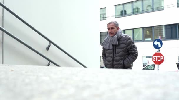 暖かいニットのスカーフとジャケットの中年の男は 背後に停止し 道路標識をオンにし 建物に花崗岩の灰色の階段を登る — ストック動画